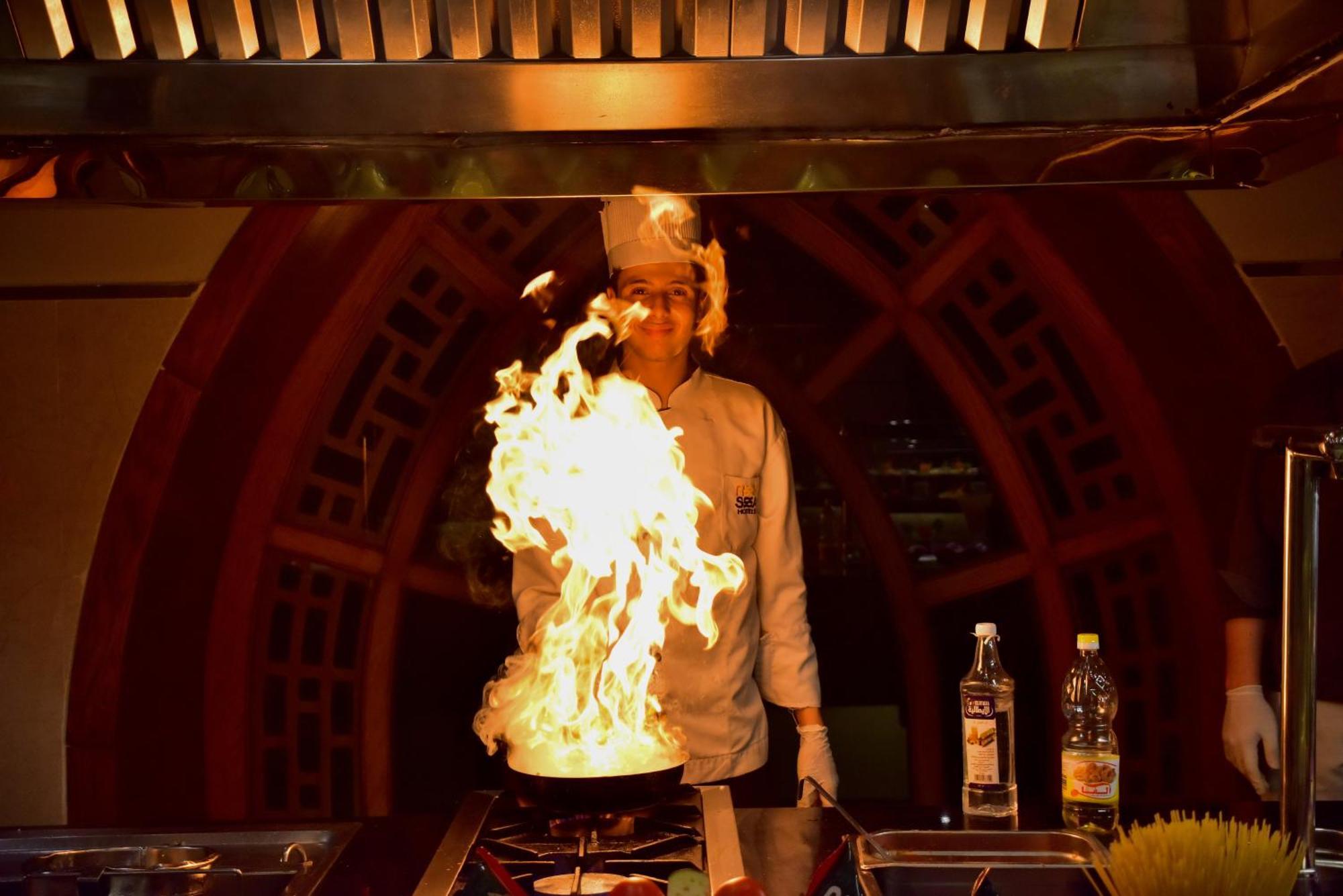 The Grand Hotel Sharm El Sheikh Exteriör bild A chef cooking with a flaming wok
